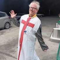 Ted in a white Crusader surcoat with a red cross and chainmail sleeve, waving